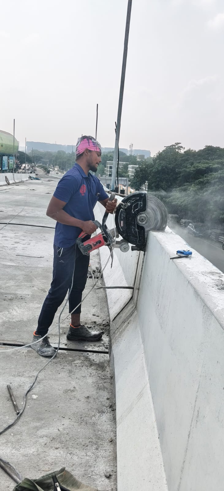 SRI Cutting Technologies operator cutting reinforced concrete barrier on flyover with heavy diamond wall saw